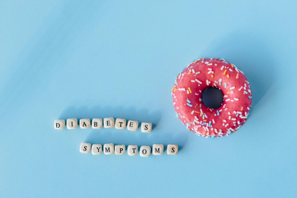 A pink frosted donut with diabetes symptoms text on a blue background, highlighting awareness.